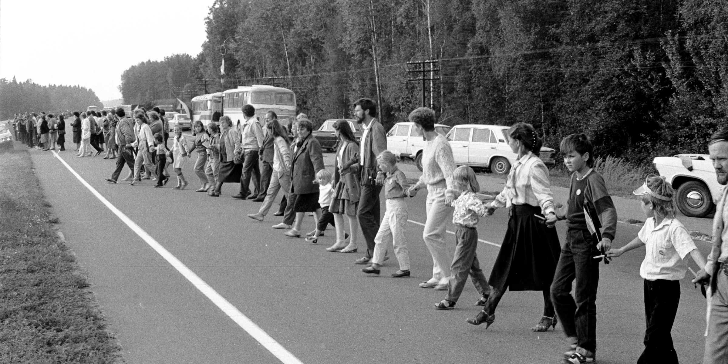 Families and children standing hand in hand along a country road in Lithuania in August 1989.